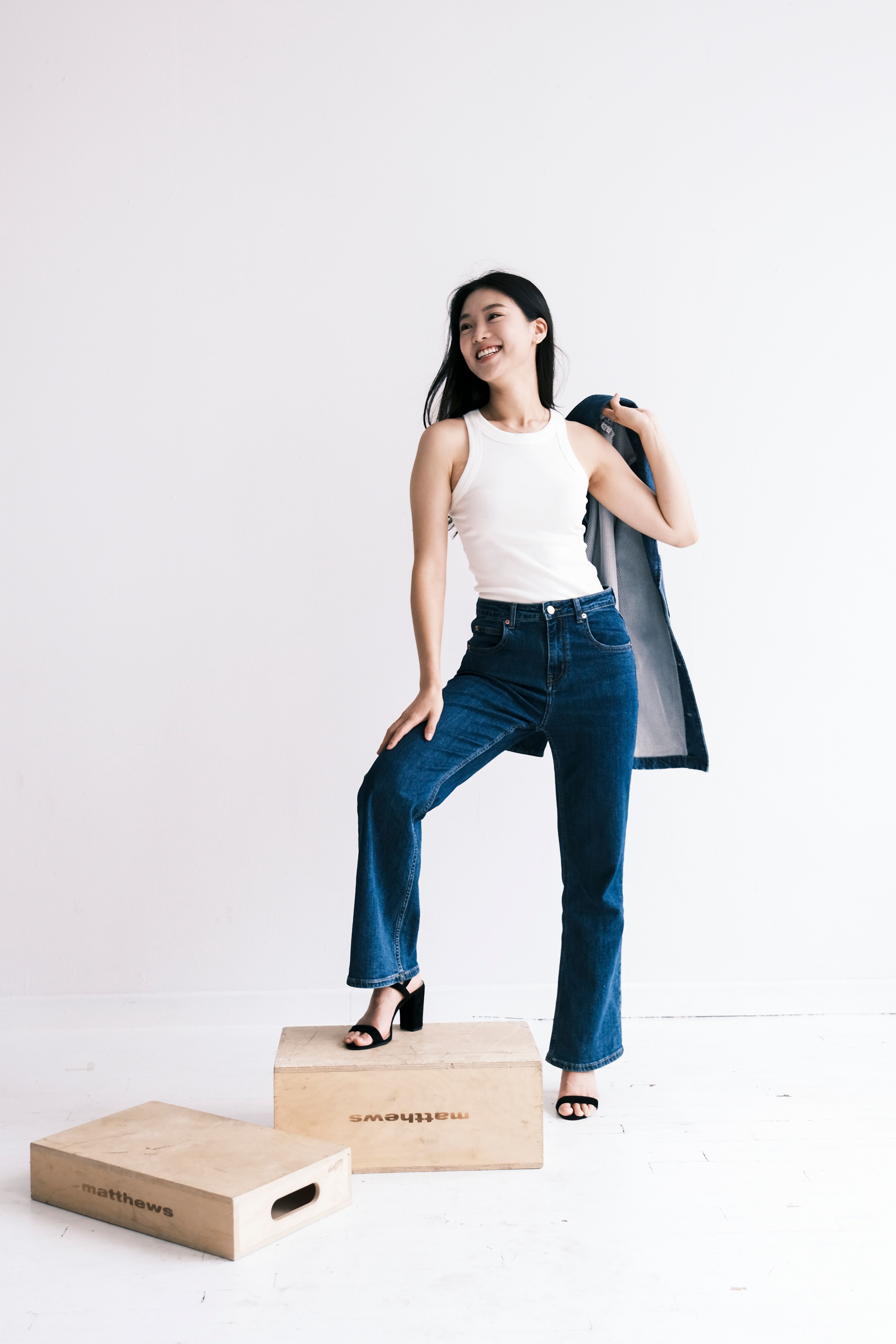 Confident young woman in denim posing against a white backdrop, exuding modern style and joy.
