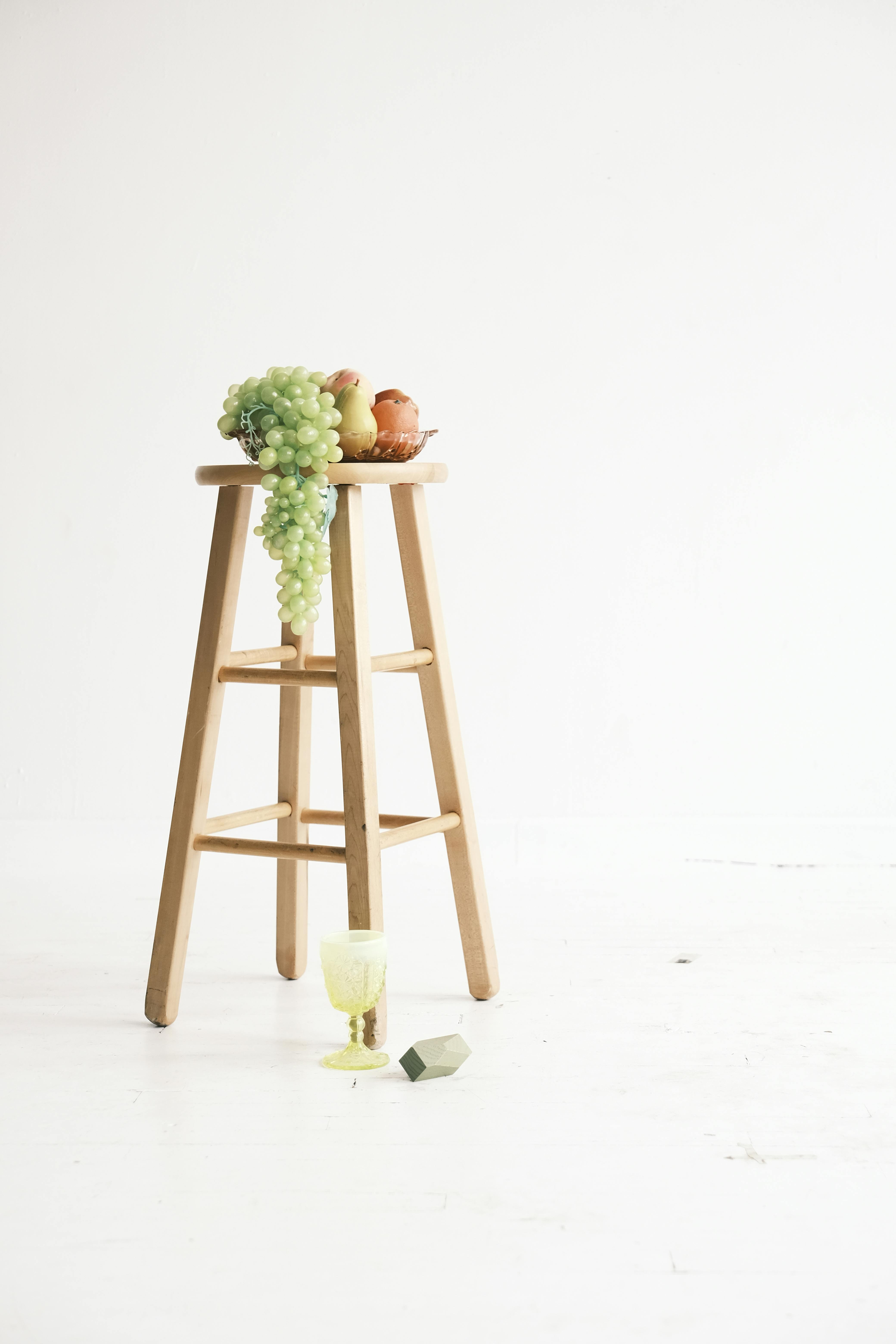 Elegant still life with fruits on a wooden stool in a bright studio.