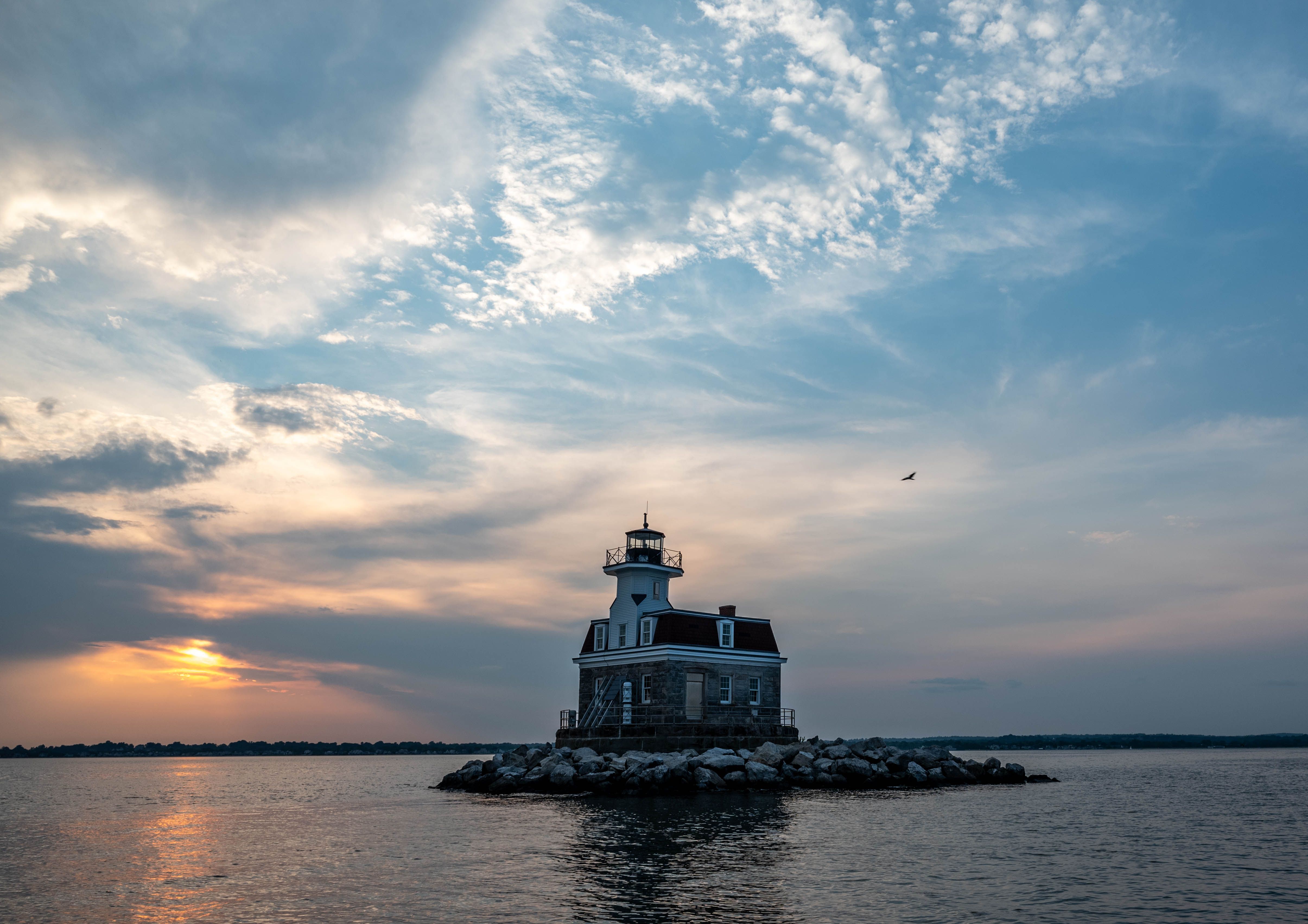 A lighthouse sits on an island in the middle of the water · Free Stock ...