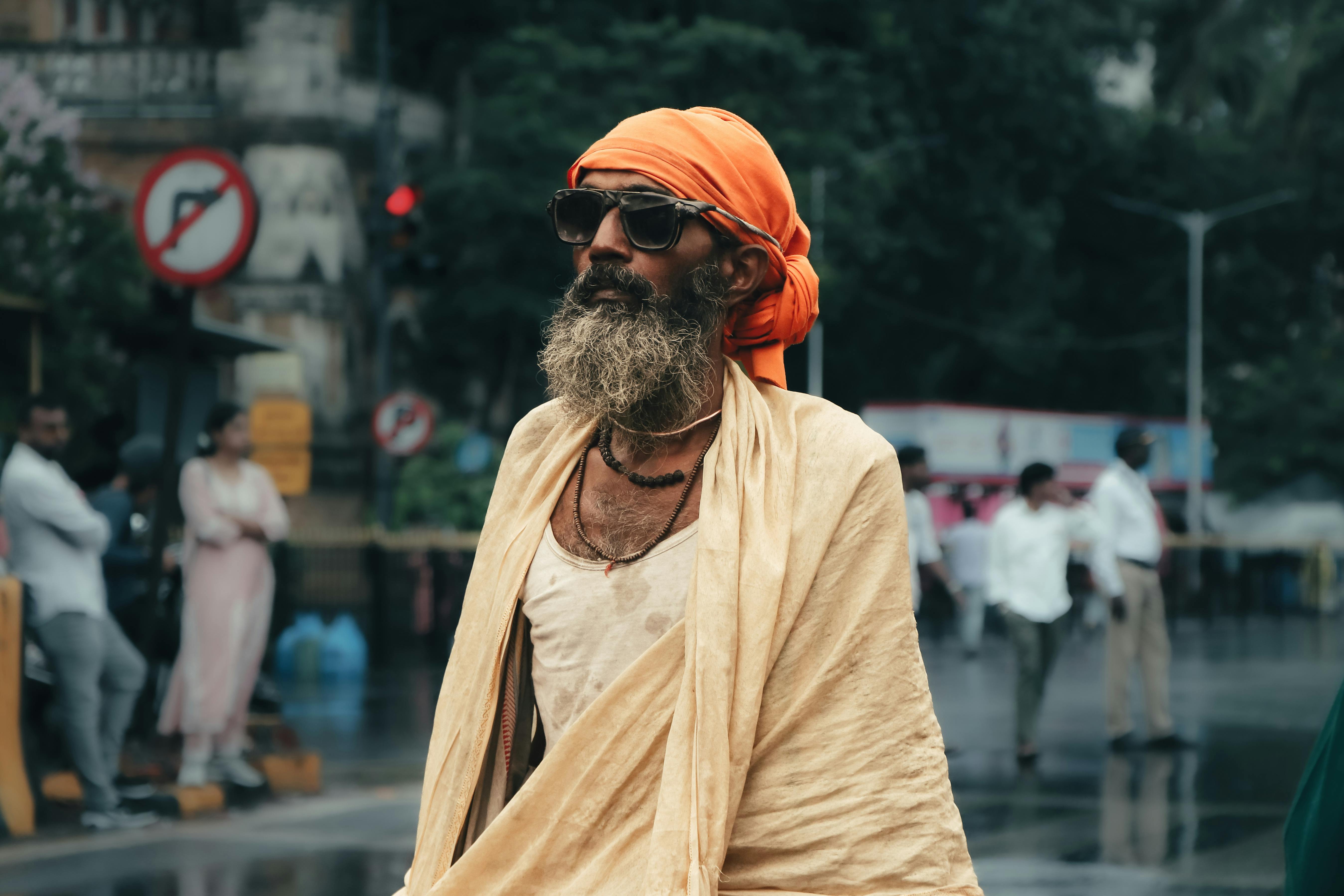 an old man with a beard and turban walking on the street