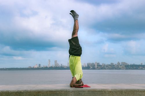Free A person performs a yoga headstand on Marine Drive, Mumbai with the city skyline in the background. Stock Photo