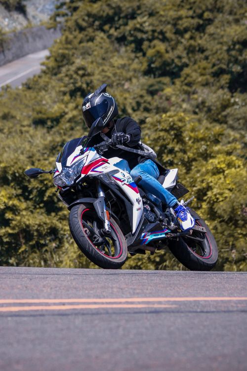 Free Motorcyclist in motion on a winding road amidst lush greenery, showcasing speed and agility. Stock Photo