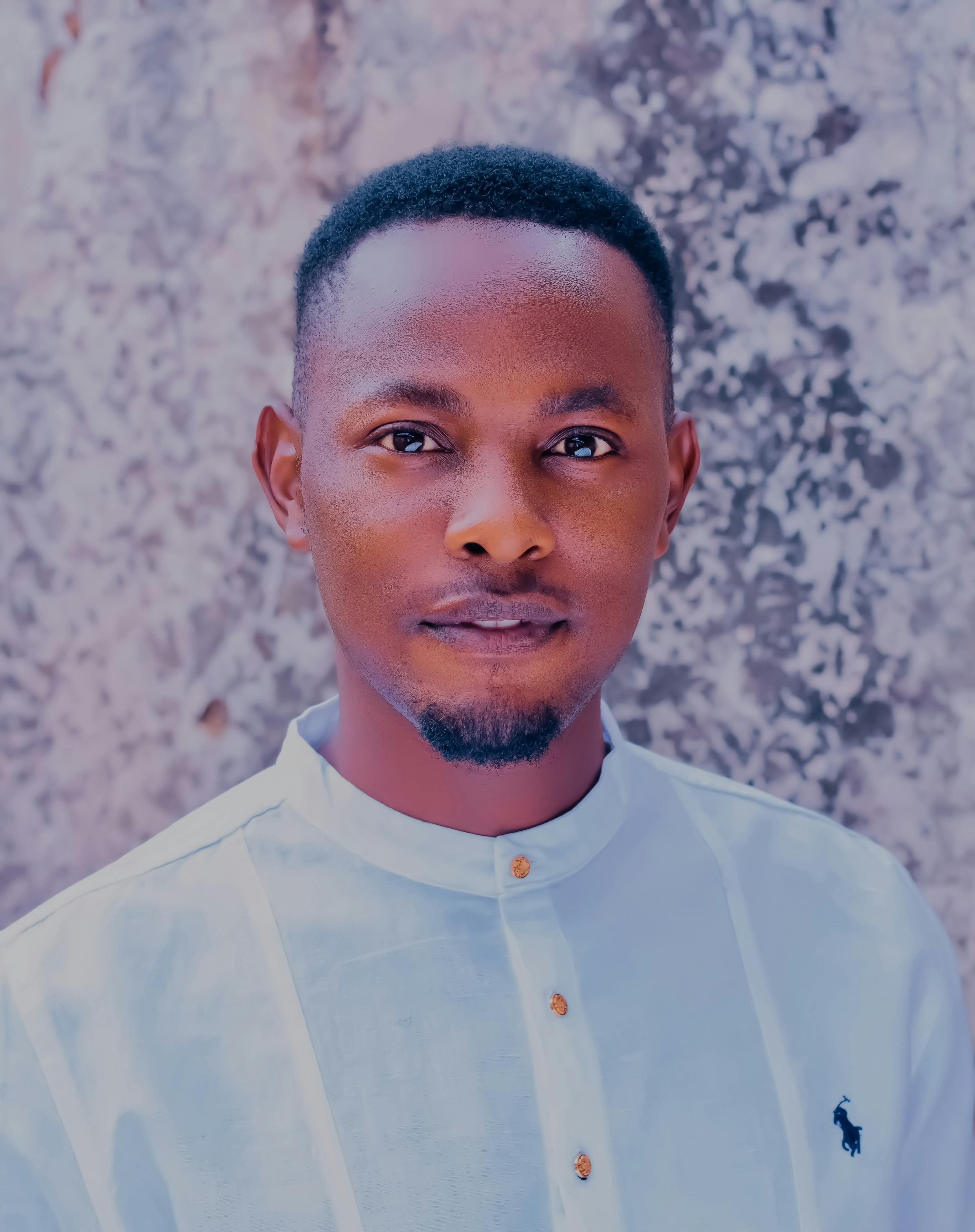Close-up portrait of a young man wearing a traditional white shirt against a textured wall.