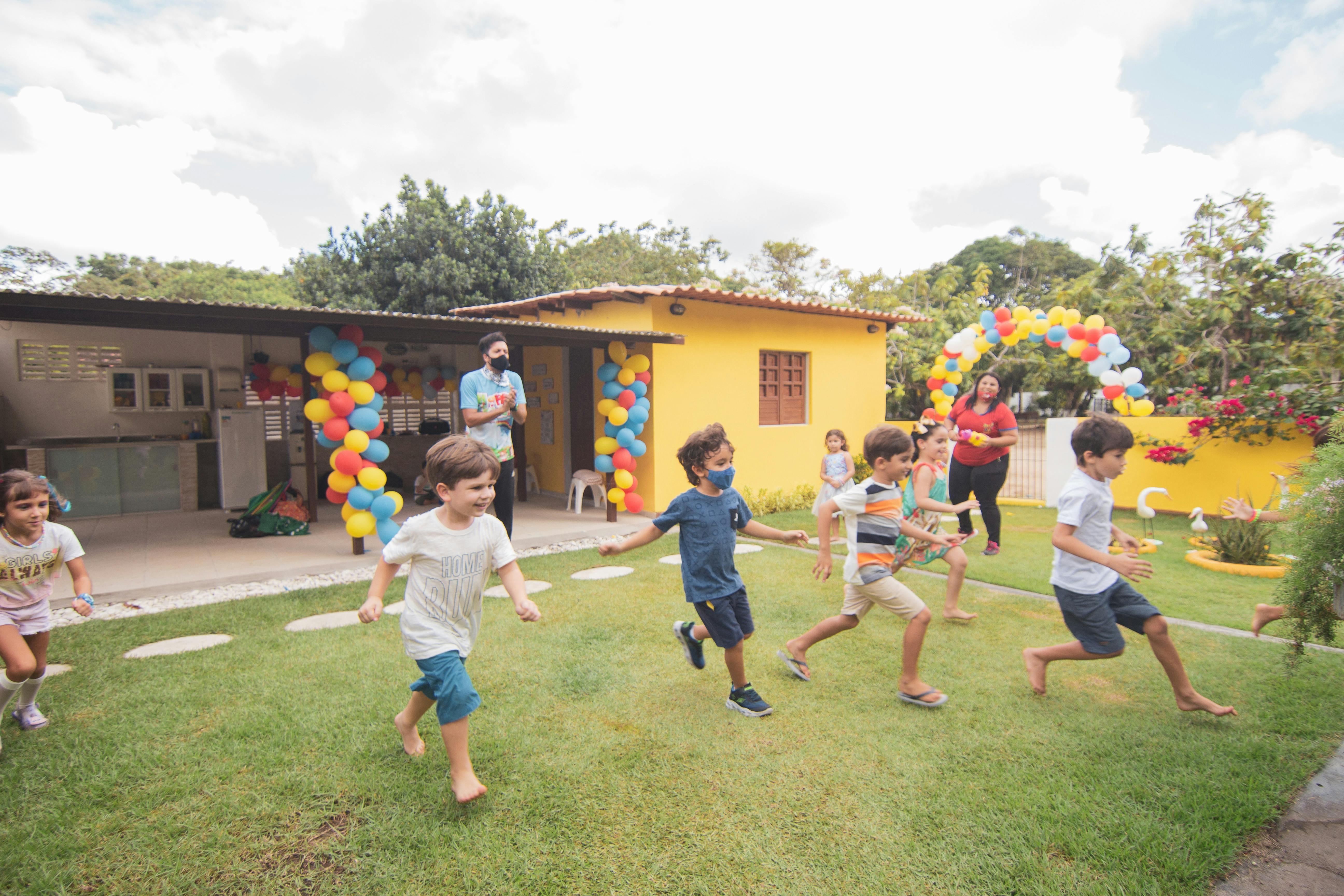 kids running in front of a house with balloons