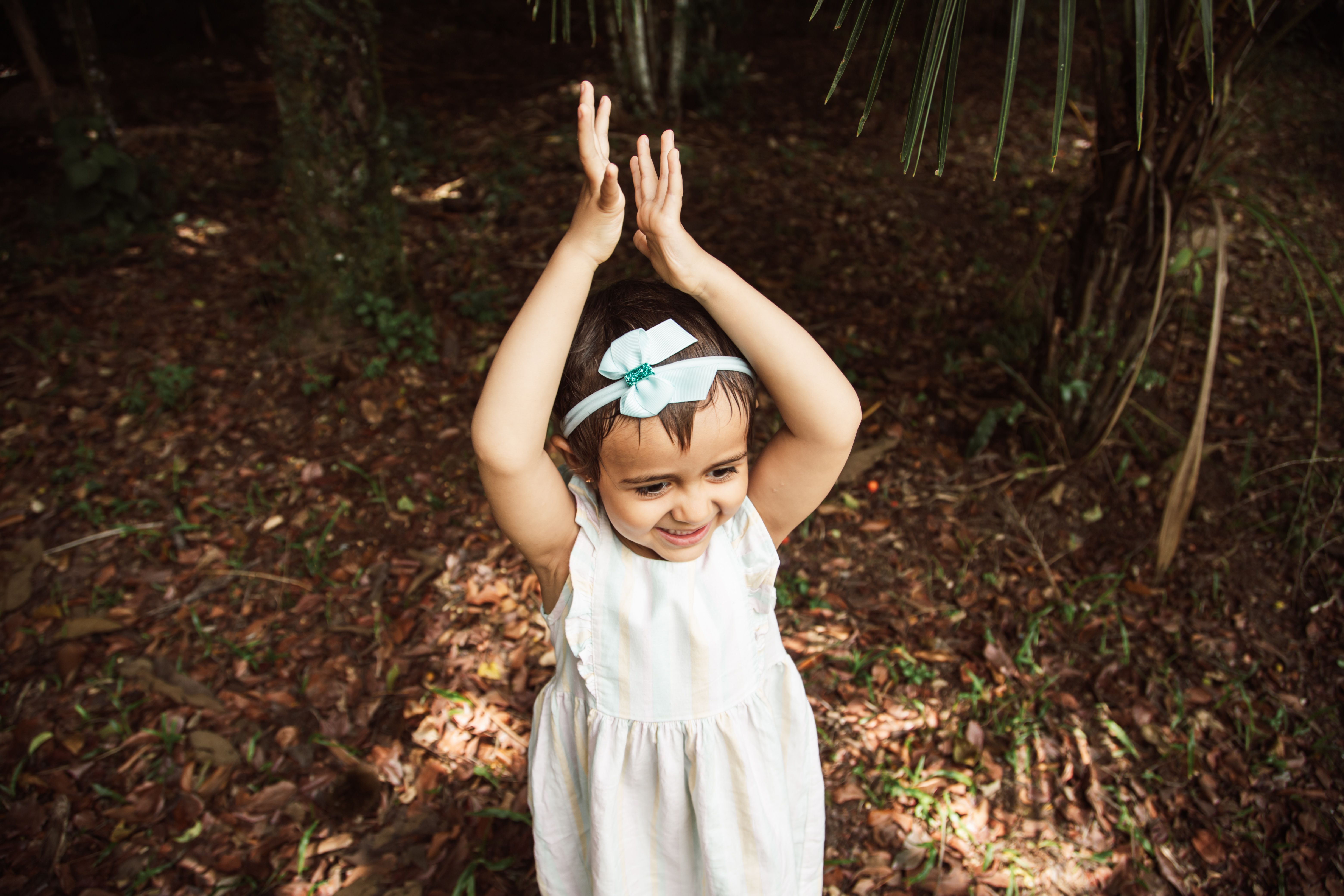 A little girl in a white dress is standing in the woods · Free Stock Photo