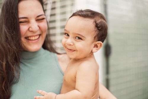Free A heartwarming image of a mother and baby sharing a joyful, affectionate moment indoors. Stock Photo