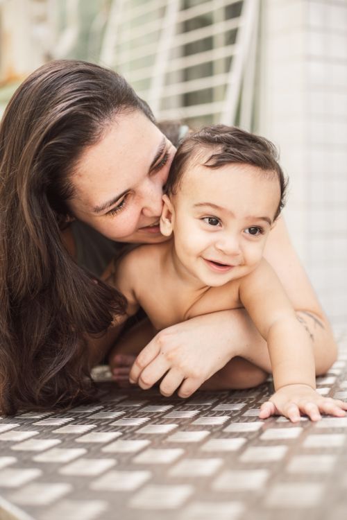 Free A joyous moment of a mother playfully embracing her smiling baby indoors. Stock Photo