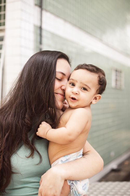 Free A loving mother embraces her joyful baby boy outdoors, capturing a sweet family moment. Stock Photo