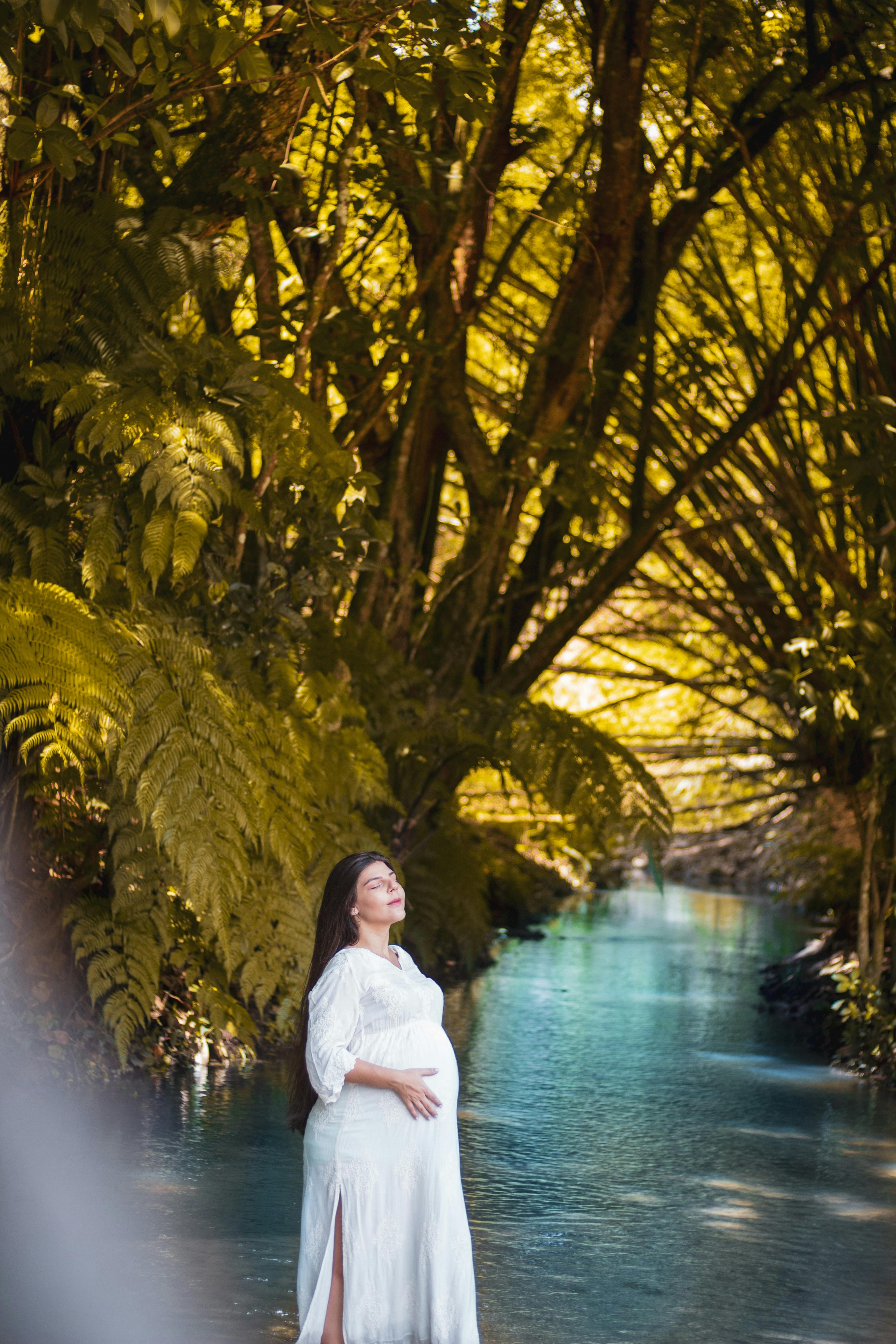 a pregnant woman standing in the middle of a river