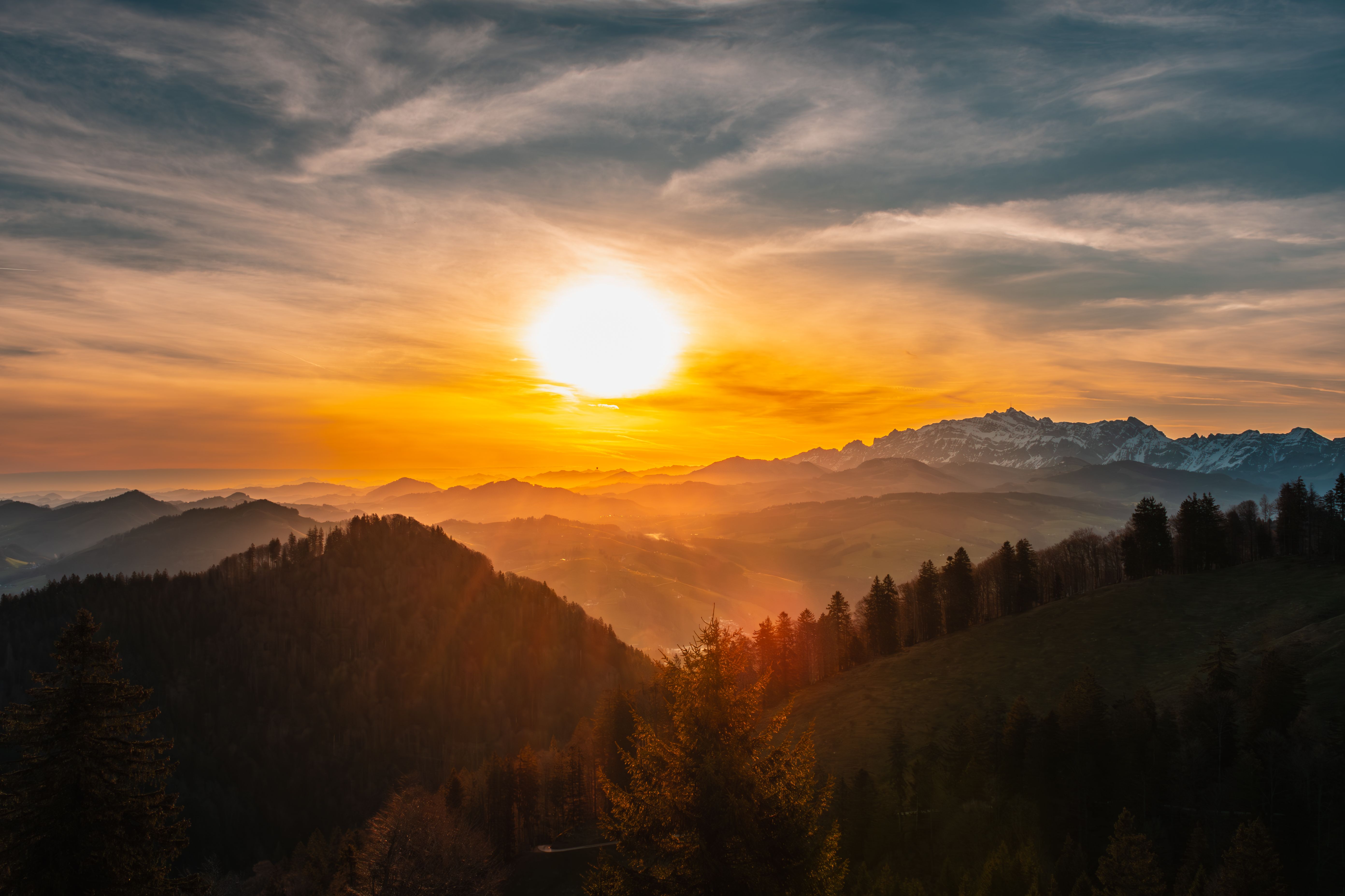 The sun sets over a mountain range with trees and mountains · Free ...
