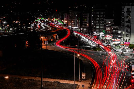 Long exposure night photo of city with vibrant vehicle light trails creating dynamic patterns.