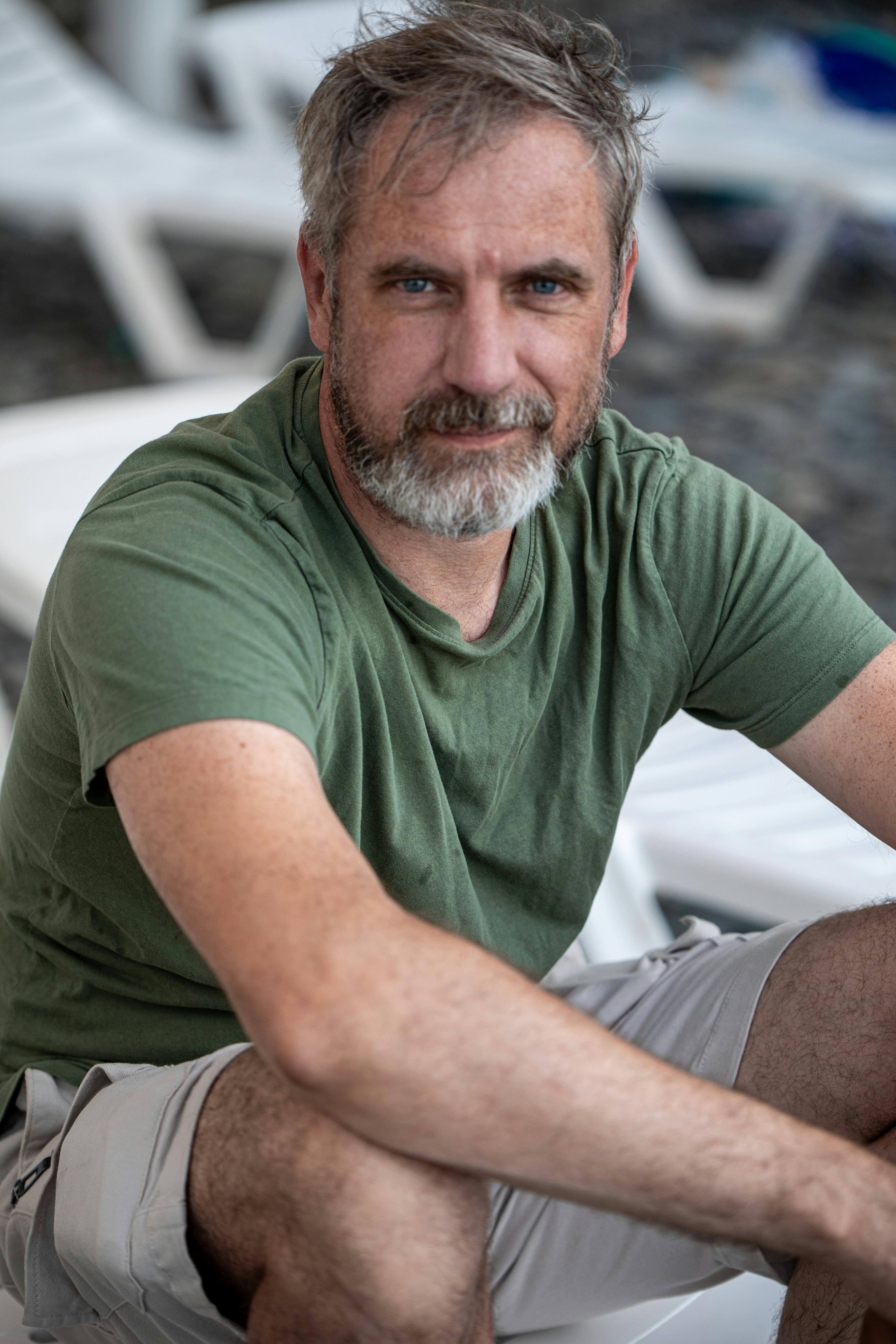 a man with grey hair and beard sitting on a chair