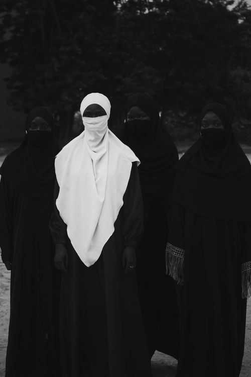Free Black and white portrait of four women wearing hijabs and veils, conveying mystery and unity. Stock Photo
