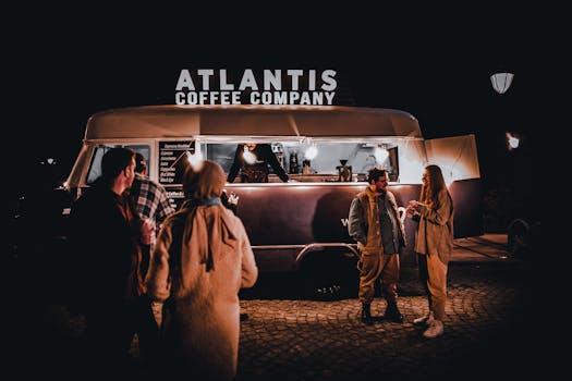 People enjoy a casual evening at the Atlantis Coffee food truck, illuminated in the night.