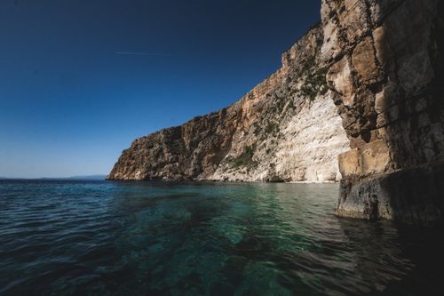 Free Majestic coastal cliff with deep blue waters under a clear sky. A perfect seascape. Stock Photo