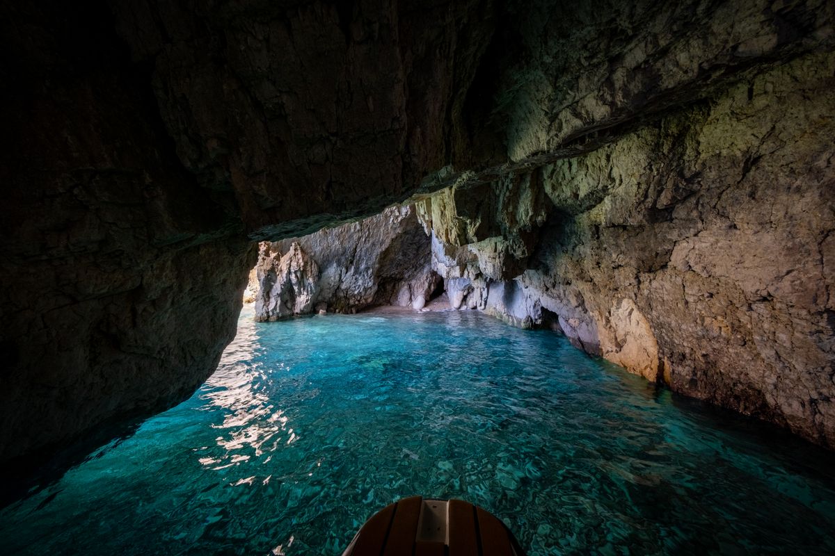 Barca in interiorul unei pesteri marine, cu apa turcoaz