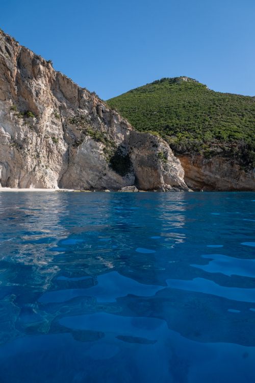 Free Discover a serene tropical beach featuring stunning cliffs and vibrant turquoise waters, perfect for travel and relaxation. Stock Photo