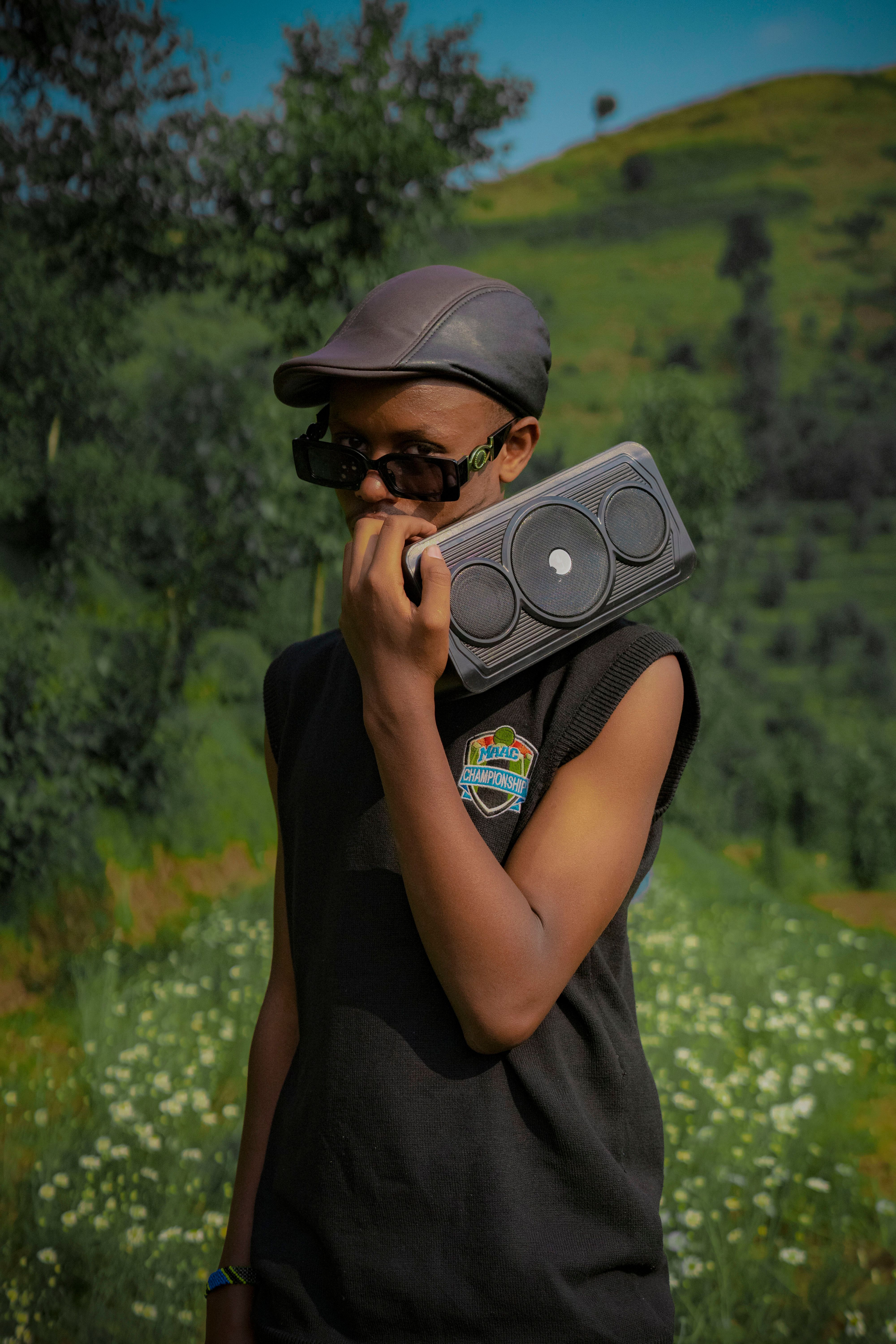 A young person carrying a boombox, enjoying the outdoors in a vibrant green field.