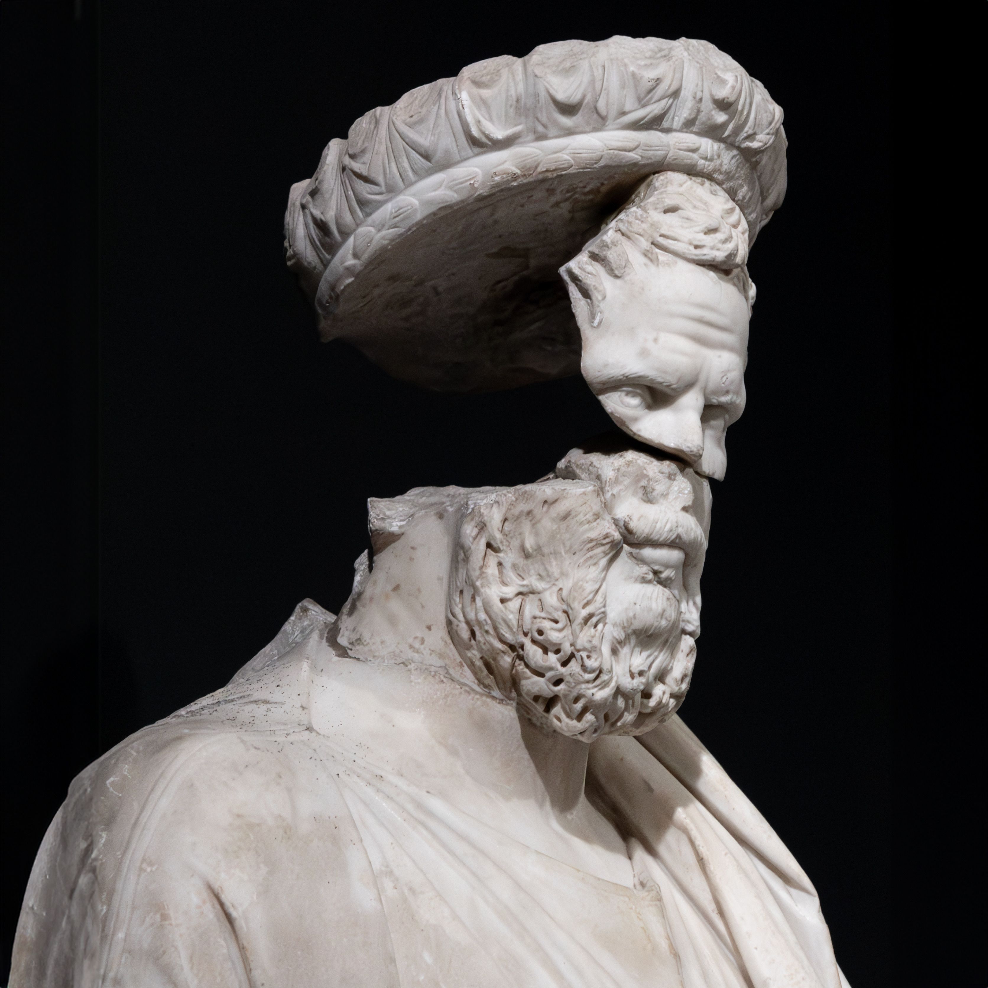 Close-up of a fragmented ancient marble sculpture with a detached headpiece.
