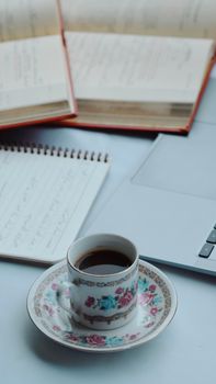A cup of coffee on a desk with an open laptop and notebooks, ideal for study sessions.