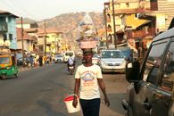 A street vendor carries goods on her head in a busy urban street of Freetown, Sierra Leone.