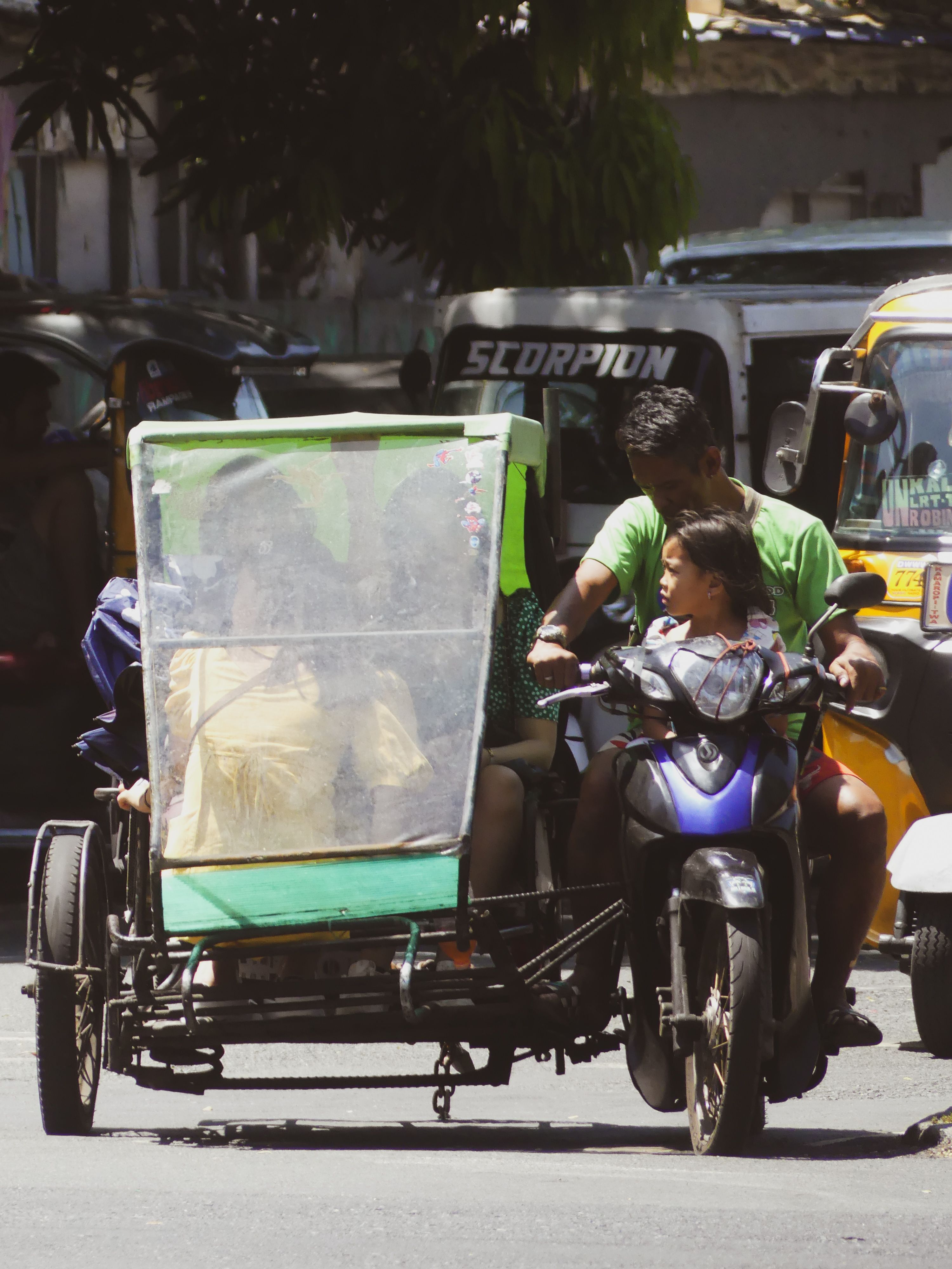 A tricycle with passengers on a bustling street in Manila, showcasing local transportation.