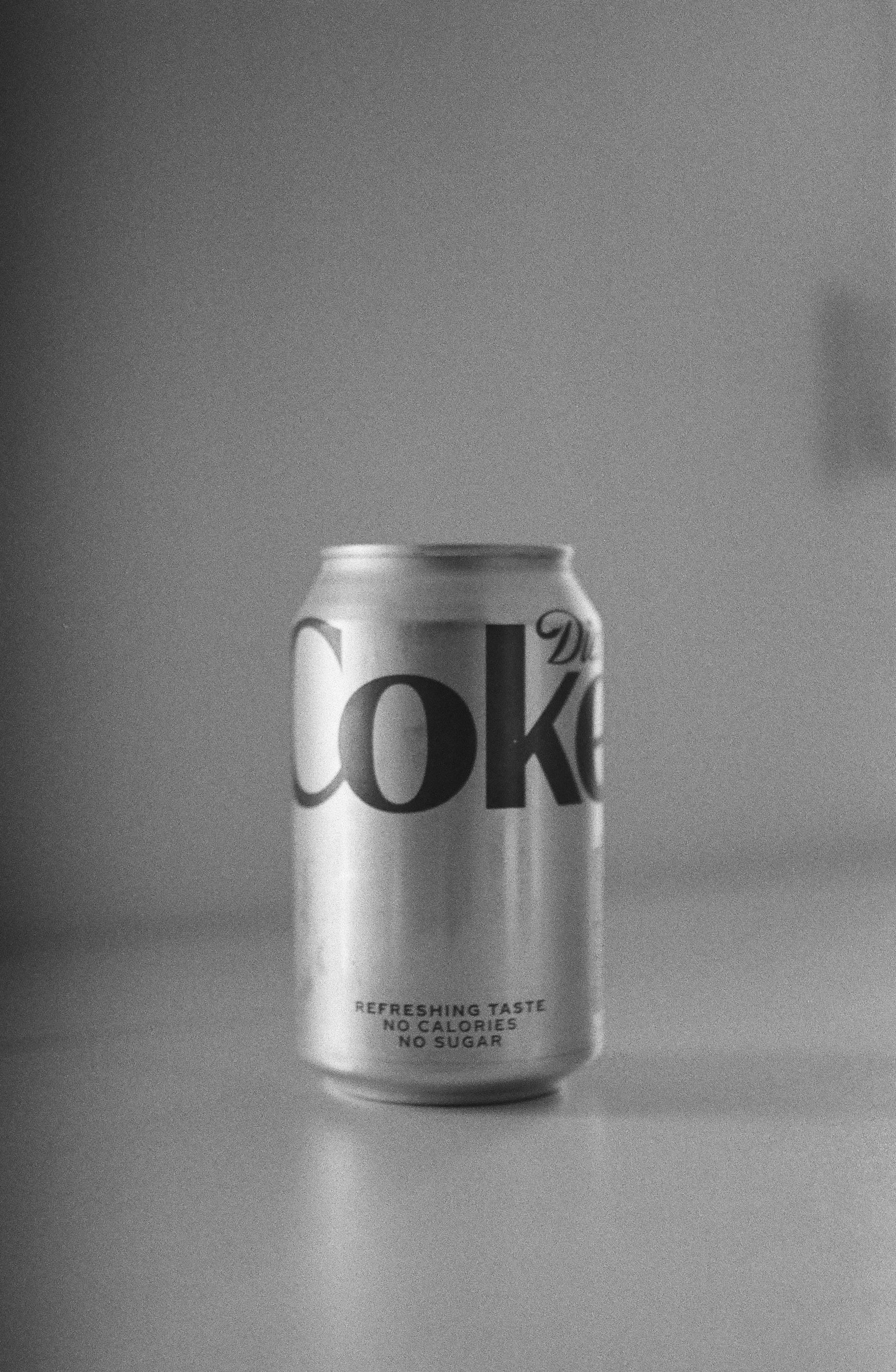 a can of coke on a table in black and white