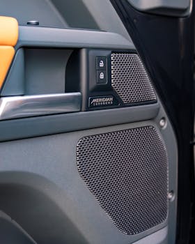 Detail of a car's interior showing a Meridian surround sound speaker and lock controls.