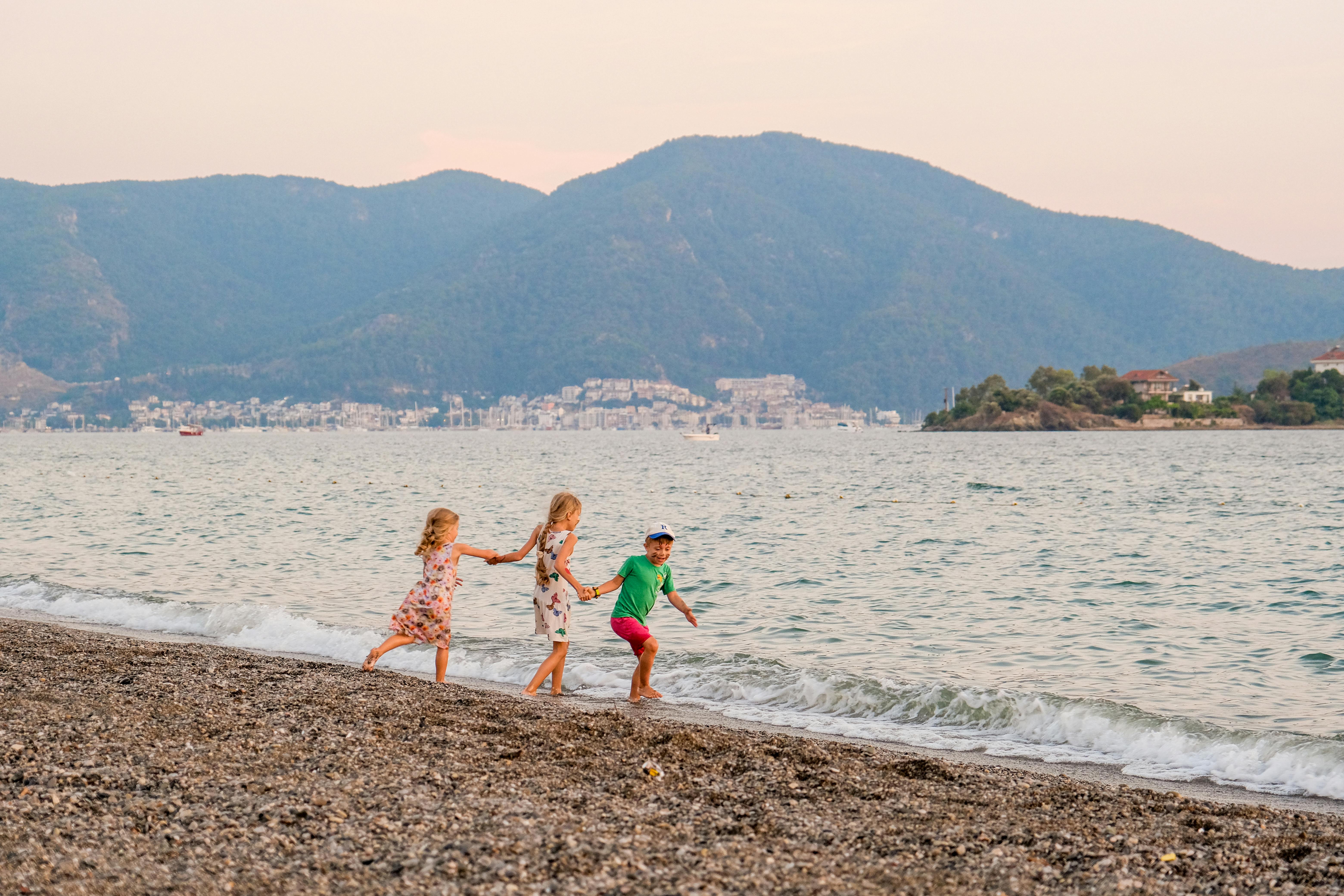 Children having fun on Fethiye's beach in summer, capturing joyful and playful moments by the sea.
