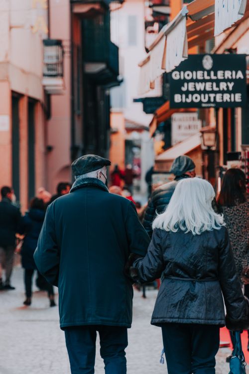 Free Senior couple walking hand in hand along a lively street. Urban shopping scene. Stock Photo
