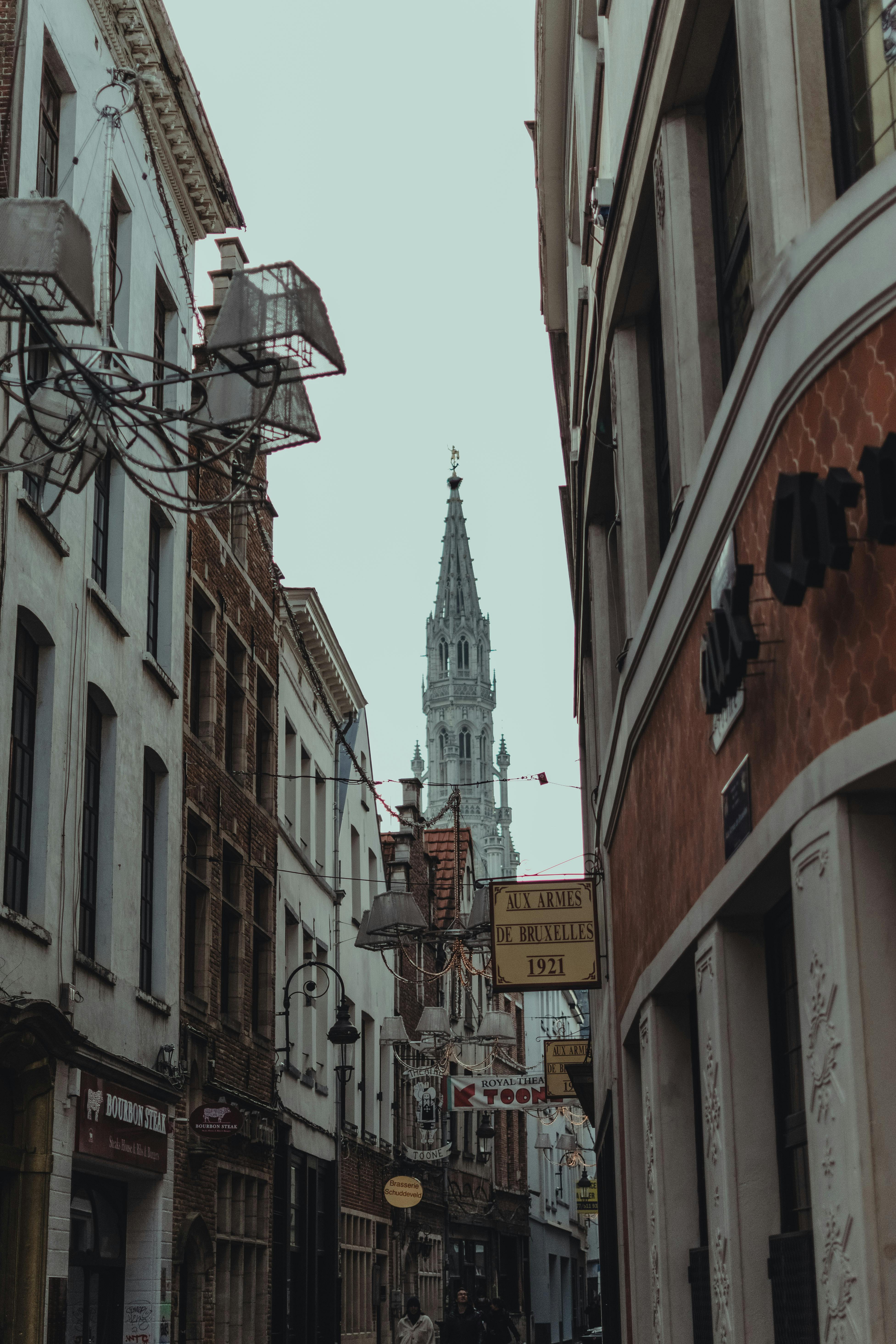 a narrow street with buildings and a church tower