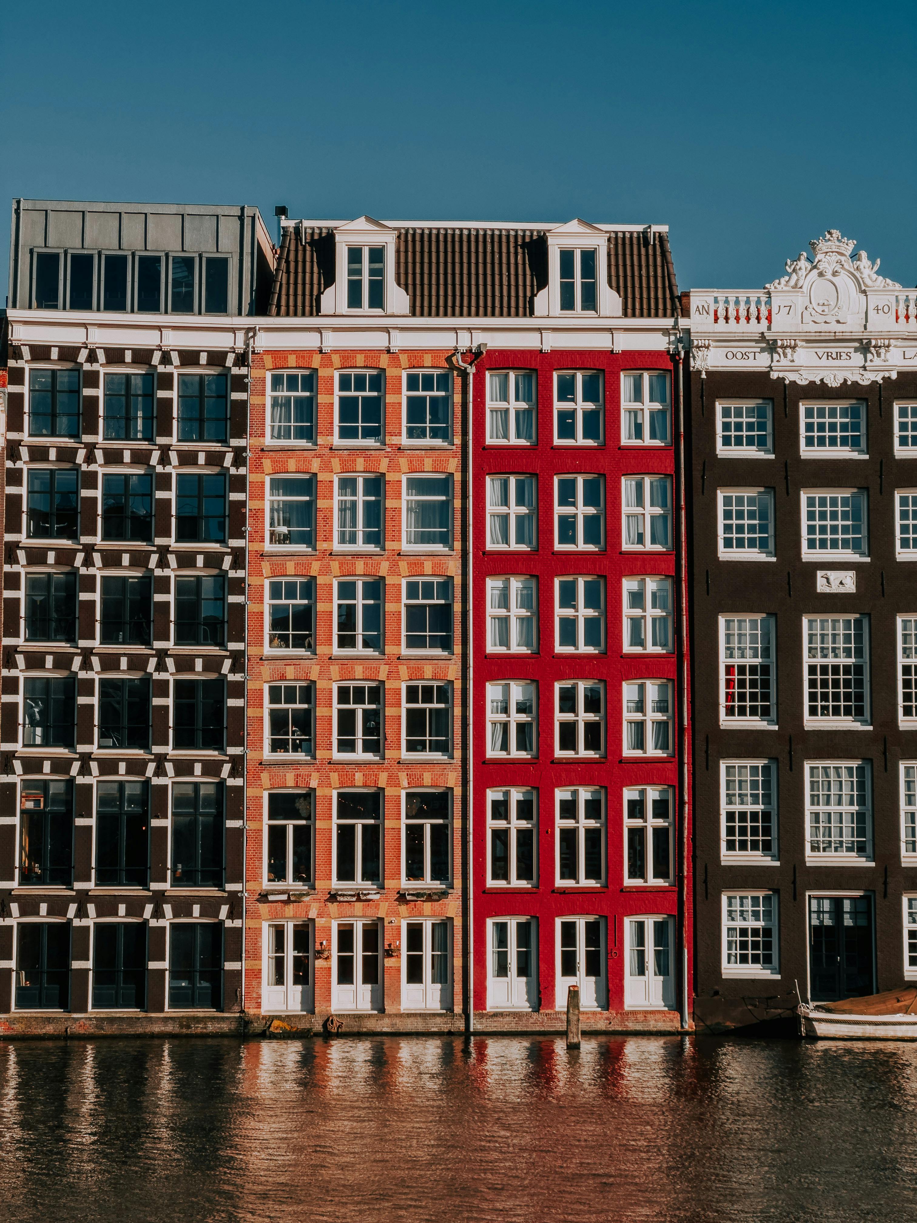 Vibrant canal houses reflecting in water, classic Amsterdam architecture.