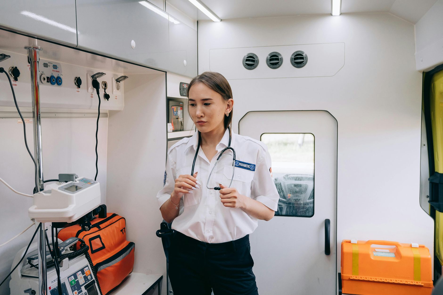 A professional female paramedic inside an ambulance, ready for emergency response with medical equipment.