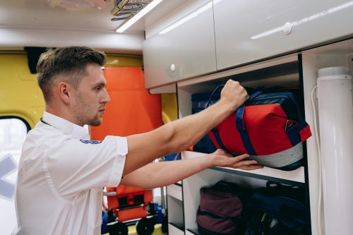 Free A paramedic places a medical bag on a shelf inside an ambulance, preparing for emergencies. Stock Photo