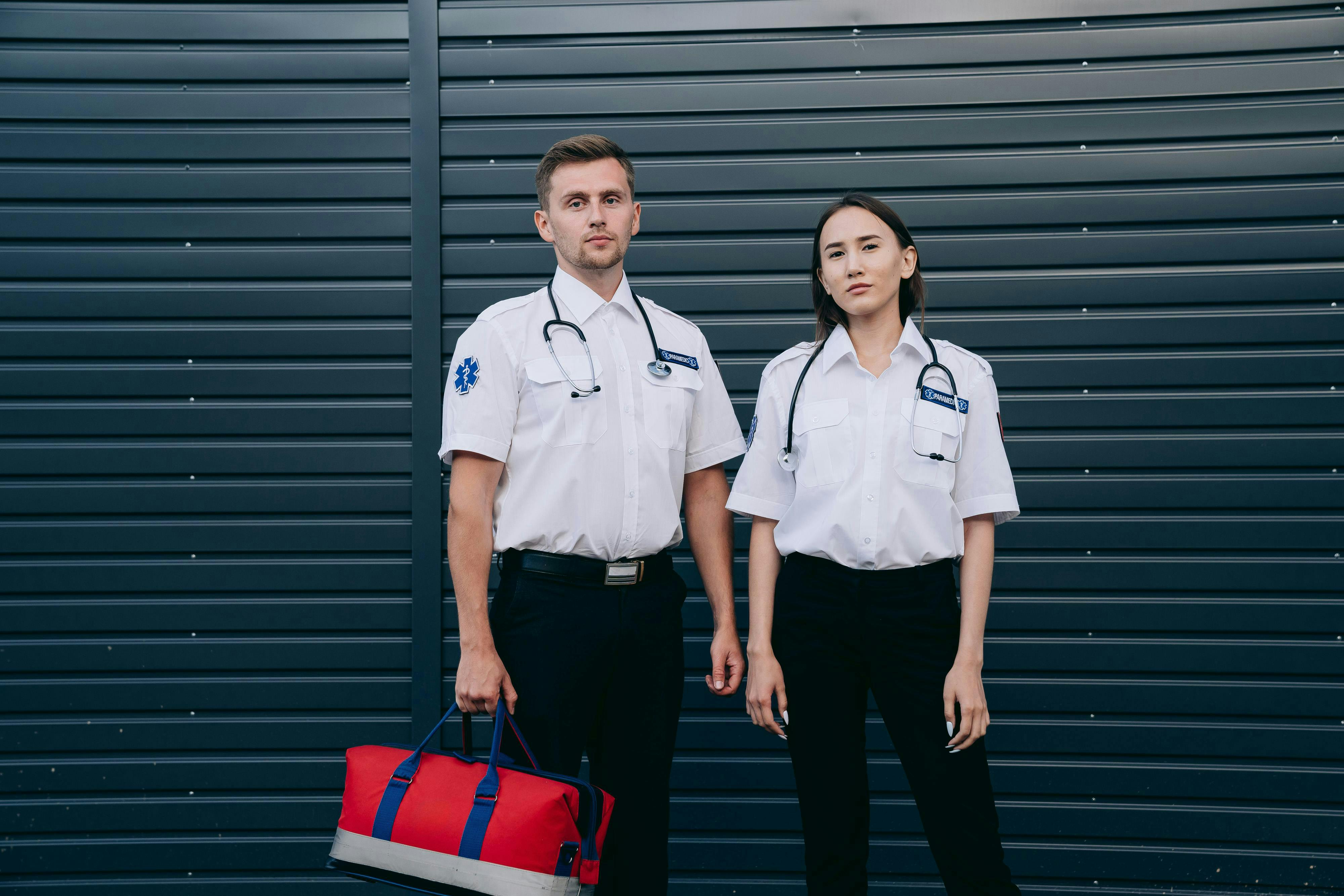 A confident pair of paramedics stand ready with medical equipment, exemplifying teamwork and professionalism.