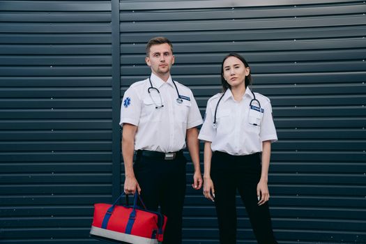 A confident pair of paramedics stand ready with medical equipment, exemplifying teamwork and professionalism.