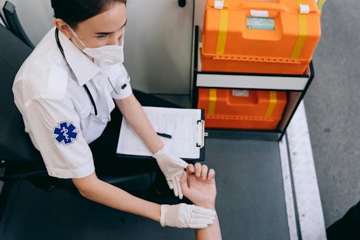 A paramedic in a mask checks a patient's pulse inside an ambulance for medical assessment.