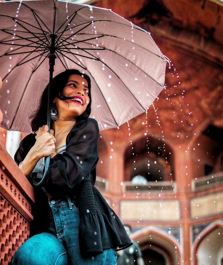 Low-angle View Of Woman Holding Umbrella Under The Rain