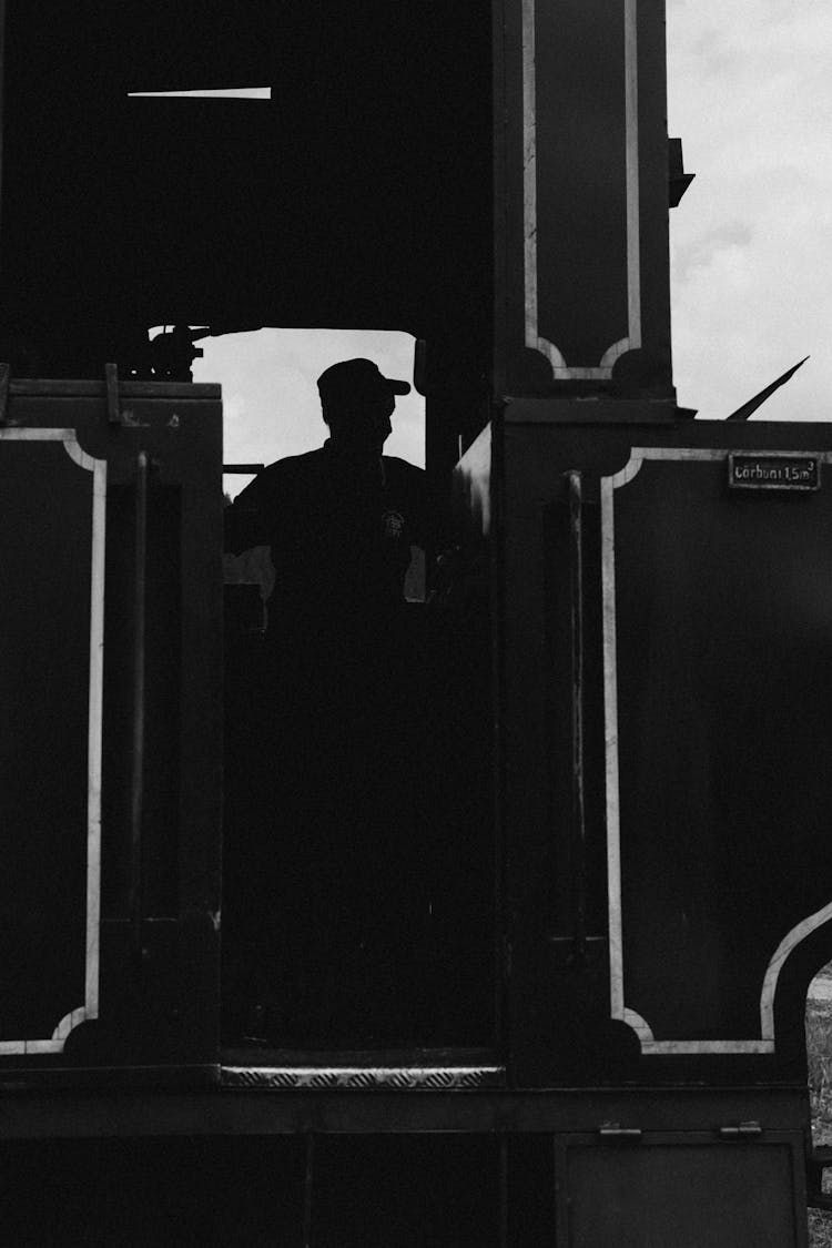 A Black And White Photo Of A Man Standing In The Doorway Of A Train