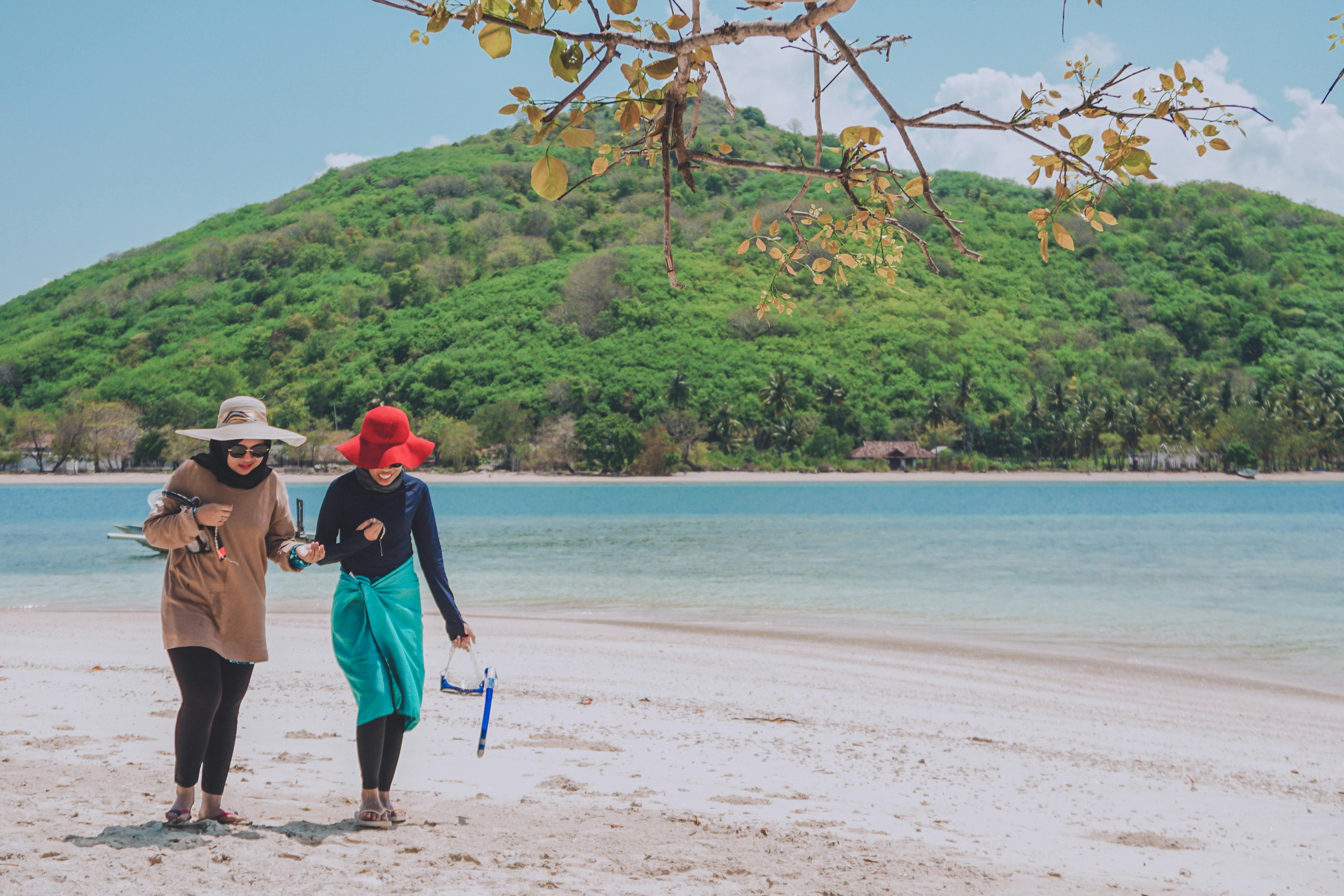 photo of two women walking on seashore