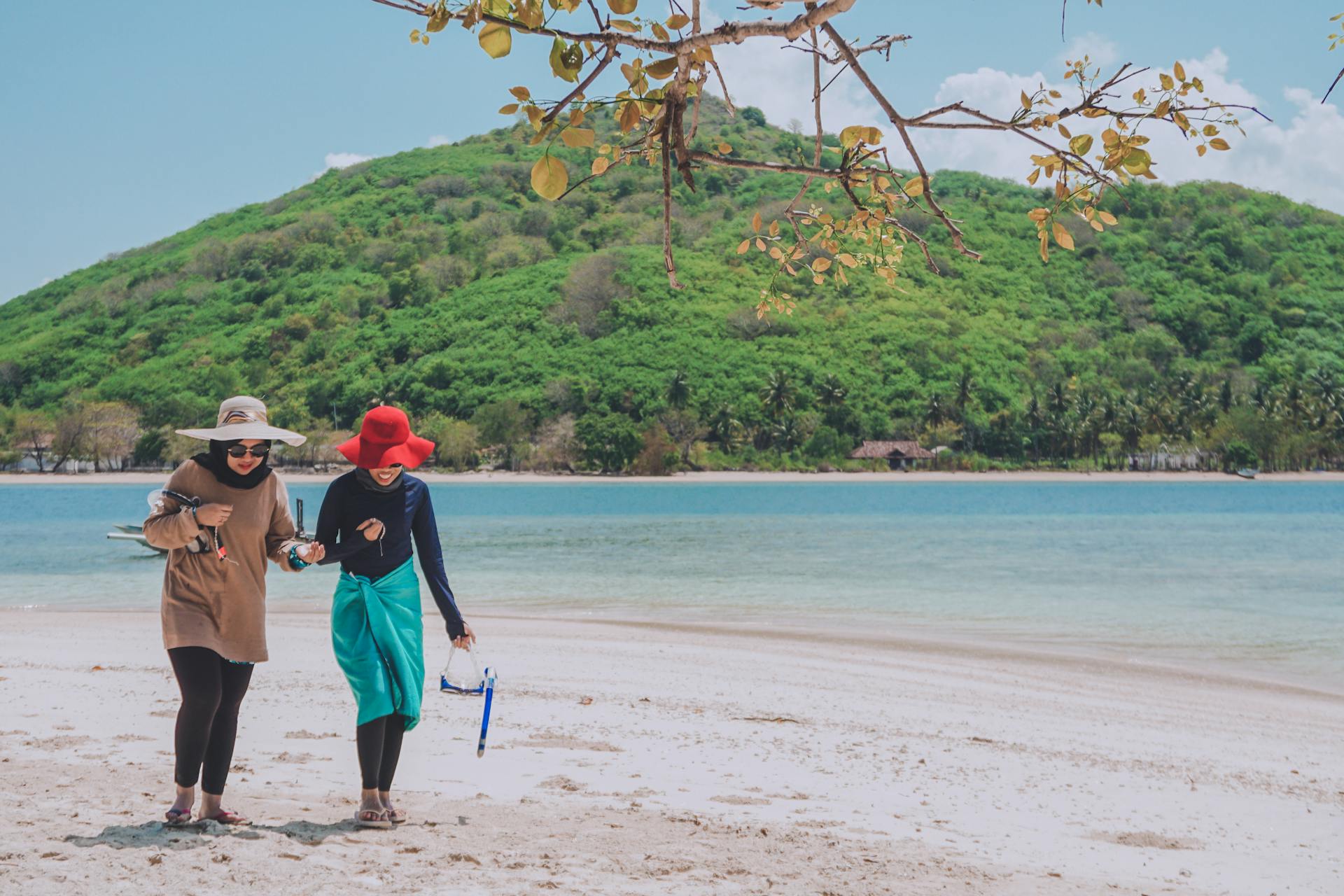 Two women strolling on a scenic tropical beach in West Nusa Tenggara, Indonesia.