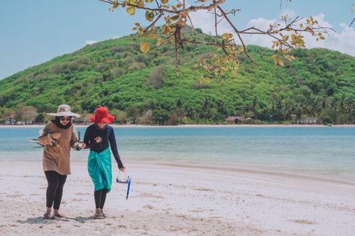 Free Two women strolling on a scenic tropical beach in West Nusa Tenggara, Indonesia. Stock Photo