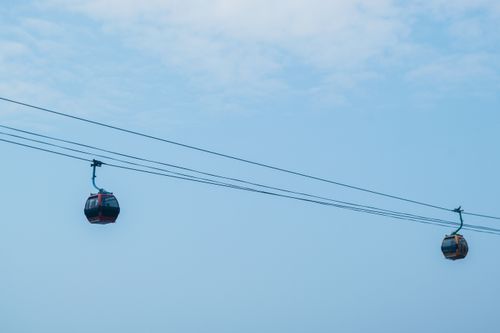 Free Two gondolas suspended on cables in a clear blue sky, showcasing modern transportation. Stock Photo
