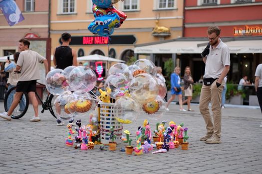 A lively street market with balloons, toys, and people enjoying a festive atmosphere in Wroclaw.
