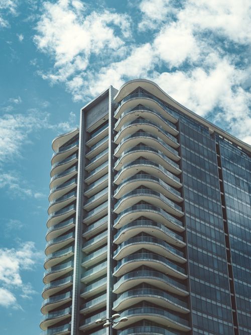 Free High-rise building with curved balconies against a cloudy blue sky. Stock Photo