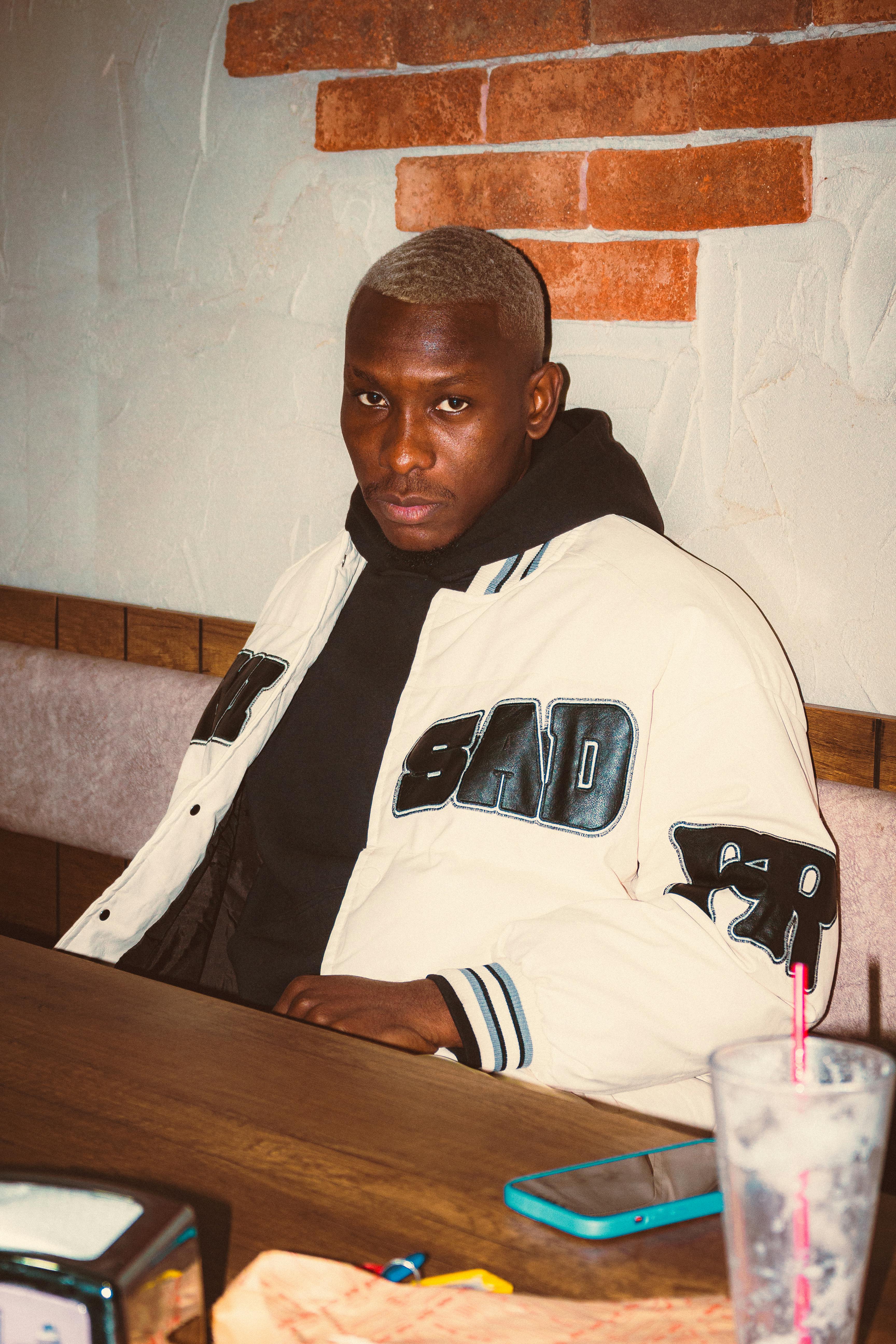 Portrait of a man sitting in a cafe wearing a stylish jacket.
