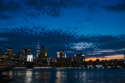 Beautiful view of the New York City skyline during dusk with the Brooklyn Bridge and colorful sky.