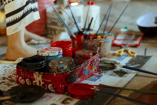 A person is painting on a table with a tray of paint