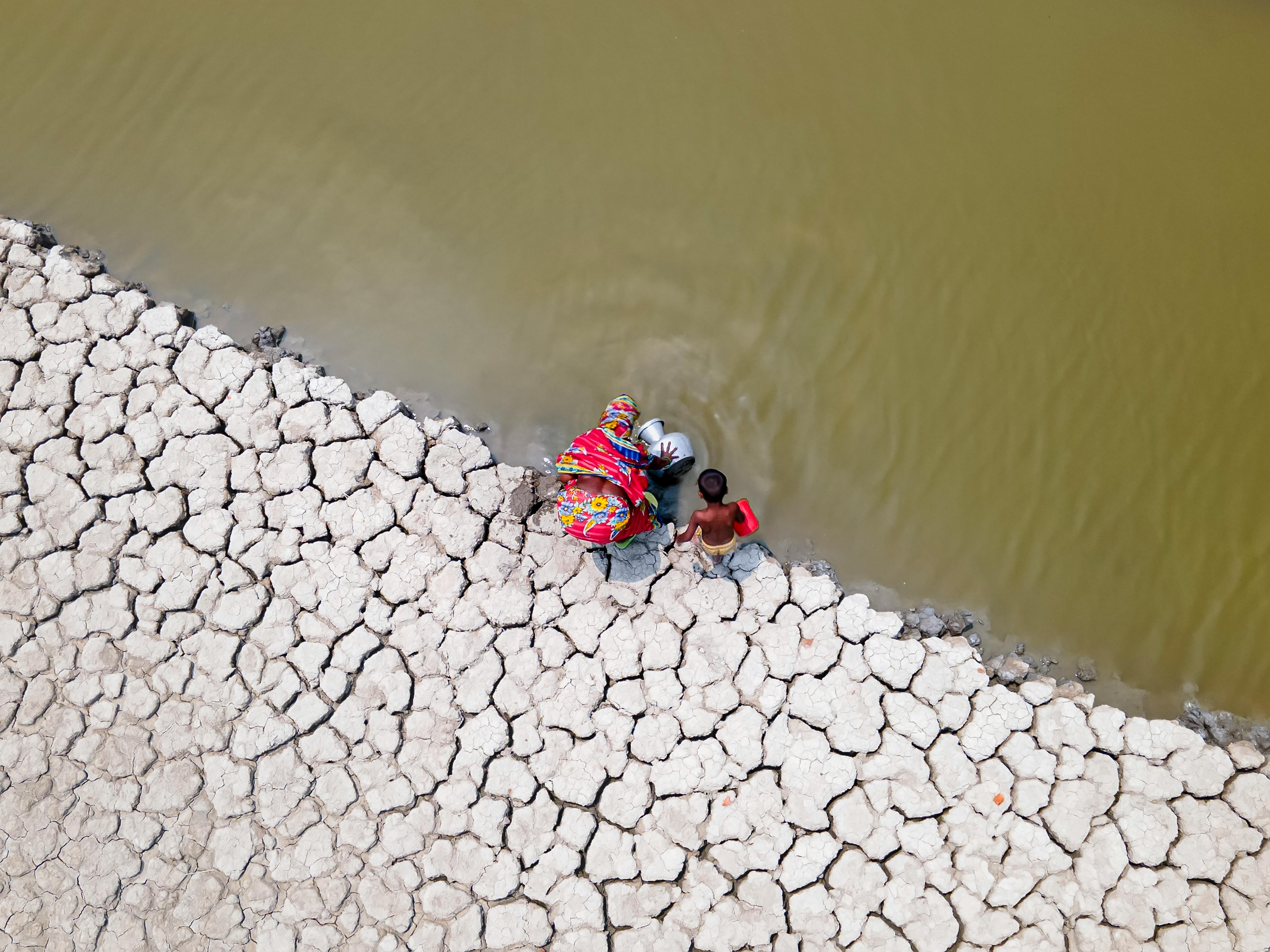 Free Aerial view of a woman and child collecting water in drought-affected Bangladesh. Stock Photo