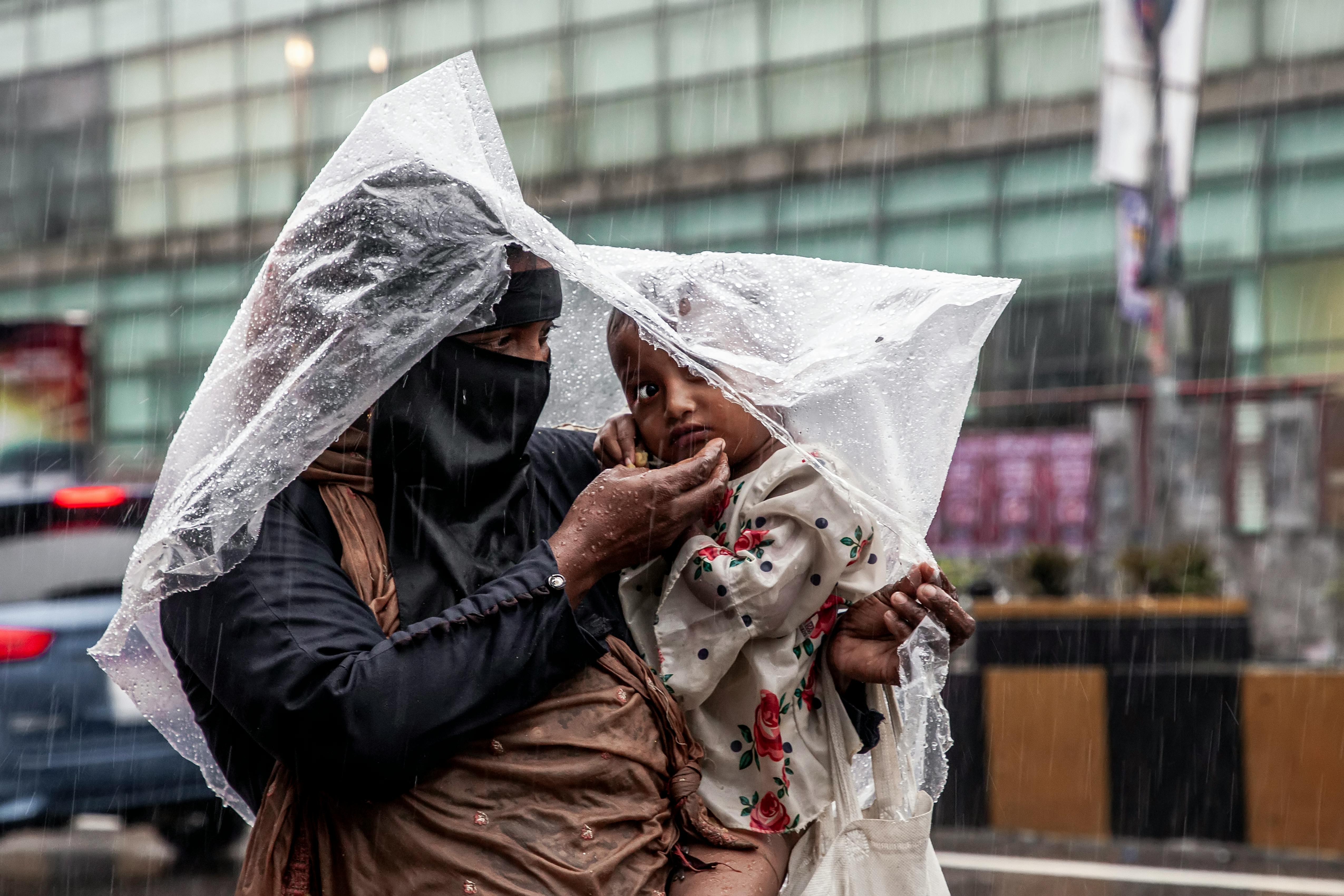 woman with child under plastic cover during rain